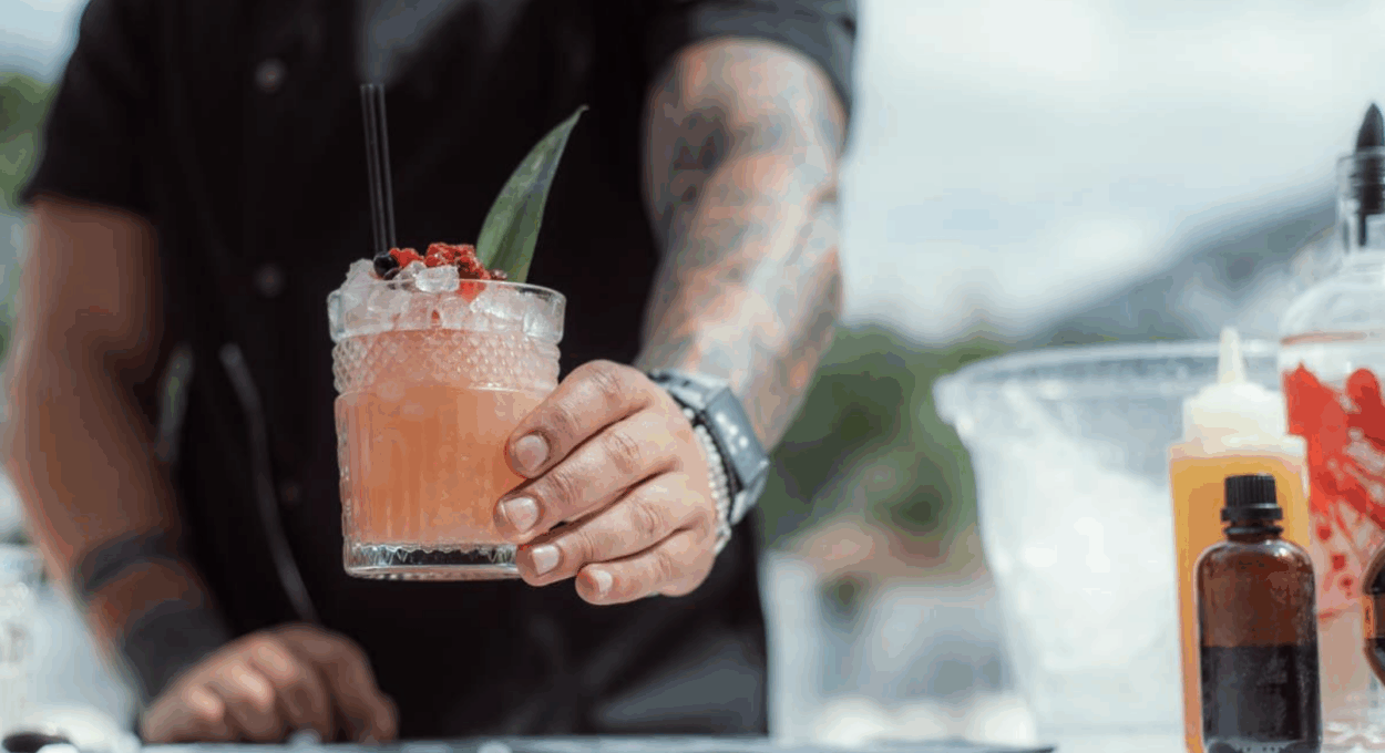 Een barman zet een oranje drankje op de bar
