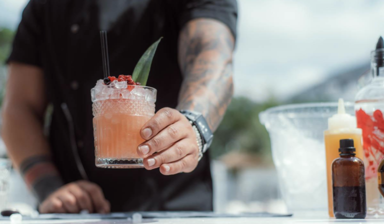 Een barman zet een oranje drankje op de bar