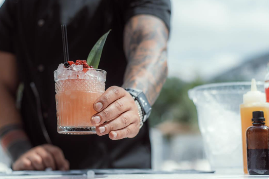 Een barman zet een oranje drankje op de bar