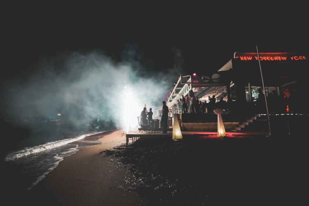 Een beach club aan zee in de nacht met rook en lichteffecten.