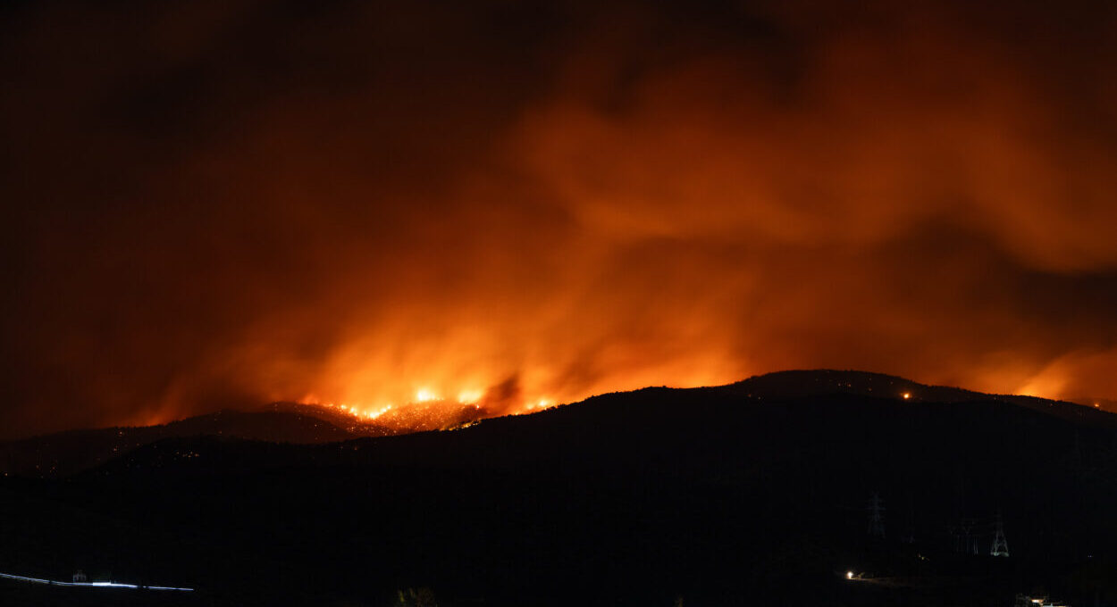 Gloeiende heuvels in het donker tijdens een hevige natuurbrand bij Ierapetra op Kreta, met rookwolken en vuurgloed aan de horizon