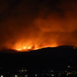 Gloeiende heuvels in het donker tijdens een hevige natuurbrand bij Ierapetra op Kreta, met rookwolken en vuurgloed aan de horizon