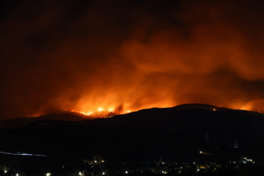 Gloeiende heuvels in het donker tijdens een hevige natuurbrand bij Ierapetra op Kreta, met rookwolken en vuurgloed aan de horizon