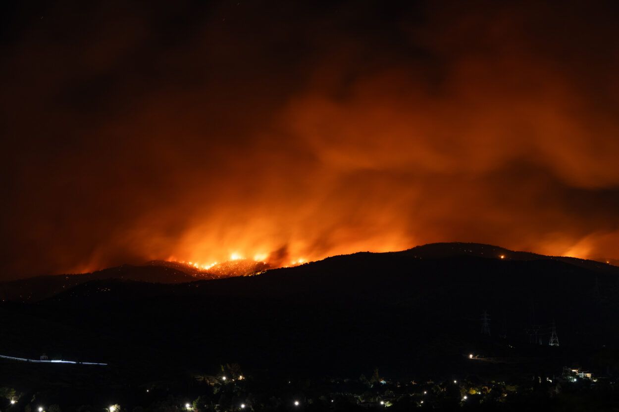Gloeiende heuvels in het donker tijdens een hevige natuurbrand bij Ierapetra op Kreta, met rookwolken en vuurgloed aan de horizon