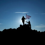 Silhouet van Griekse militairen met de Griekse vlag op een bergtop bij zonsondergang